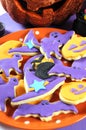 Happy Halloween orange and purple sugar cookies in cat, hat, bat and pumpkin shapes - vertical closeup.