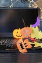 Happy Halloween, pumpkins, scary face carved on autumn leaves, mystical decor and a lantern with a burning candle, laptop on a bla