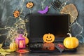 Happy Halloween, pumpkins, scary face carved on autumn leaves, mystical decor and a lantern with a burning candle, laptop on a bla