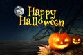 Happy Halloween. Spooky Jack O`Lantern pumpkins on wooden table under full moon Royalty Free Stock Photo