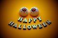 HAPPY HALLOWEEN. A cheerful face with emotion from wooden letters and two balls of eye on a bright orange background. Template for Royalty Free Stock Photo