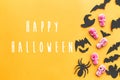 Happy Halloween text, greeting card. Halloween candy, skulls, black bats, ghost, spider paper decorations on yellow paper. Flat Royalty Free Stock Photo