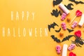 Happy Halloween text, greeting card. Halloween candy, skulls, black bats, ghost, spider paper decorations on yellow paper. Flat Royalty Free Stock Photo