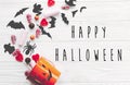 Happy Halloween text, greeting card. Halloween candy spilled from jack o lantern bucket with skulls, black bats, ghost, spider on Royalty Free Stock Photo
