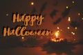 Happy Halloween text sign on pumpkin candle burning on dark orange background with lights and flying black bats. Season`s greetin Royalty Free Stock Photo