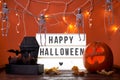 Happy Halloween white sign with black letters, pumpkin and halloween decoration. Royalty Free Stock Photo