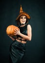 Happy Halloween Witch with bright make-up.Celebration autumn holiday Halloween. Halloween Witch with a carved Pumpkin.