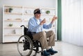 Happy handicapped senior man in wheelchair using VR headset to explore augmented reality at home Royalty Free Stock Photo