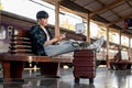 A happy Asian man is using his phone while waiting for his train at a railway station Royalty Free Stock Photo