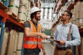 Happy handsome customer in formal clothing shaking hand of factory manager with clipboard after discussing contract