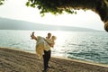 Happy handsome groom holding bride in his arms on beach at sunset Royalty Free Stock Photo