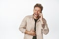 Happy handsome guy laughing on phone, talking on cellphone and chuckle carefree, standing over white background