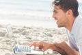 Happy handsome man on the beach using his laptop Royalty Free Stock Photo