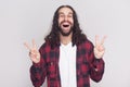 Happy handsome man with beard and black long curly hair in casual style, checkered red shirt standing with victory or peace sign Royalty Free Stock Photo