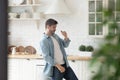 Happy handsome man dancing to music alone at kitchen.