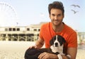 Happy handsome man with dog at seascape beach Royalty Free Stock Photo