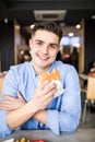 Happy handsome man eating burger in cafe Royalty Free Stock Photo