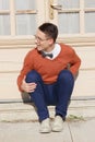 Happy handsome man with glasses and sweater sitting on steps in Royalty Free Stock Photo