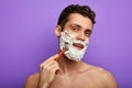 Happy handsome man looking at camera and shaving his face with razor Royalty Free Stock Photo