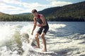 Happy handsome man wakesurfing in a lake