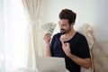 Happy handsome man work and holding money on laptop sitting in bed at the morning. Businessman working at home new normal, social Royalty Free Stock Photo