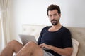 Happy handsome man working on a laptop sitting in bed at the morning. Businessman working at home new normal, social distancing Royalty Free Stock Photo