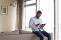 Happy handsome millennial African man touching tablet screen Royalty Free Stock Photo