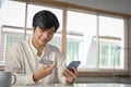 Happy Asian man using mobile banking application to transfer money or pay online bills Royalty Free Stock Photo