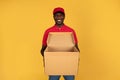 Happy handsome millennial black man courier in uniform hold empty open box