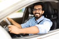 Happy eastern guy driving white auto, smiling at camera Royalty Free Stock Photo