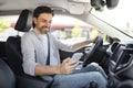 Happy handsome millennial guy driver using smartphone while driving car Royalty Free Stock Photo