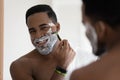 Happy handsome mixed race African man shaving with razor Royalty Free Stock Photo