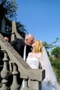 The happy handsome wedding couple are standing and kissing on stone steps in front of house. Royalty Free Stock Photo