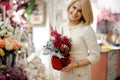 Happy handsome woman with round box of flower arrangement in her hands. Red and silver colors. Royalty Free Stock Photo