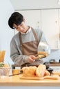 A happy Asian man pouring batter on a pan, making pancakes in his minimalist kitchen Royalty Free Stock Photo