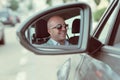 Happy handsome young business man driver in his car looking to the road side view mirror. Positive human face expression emotions Royalty Free Stock Photo
