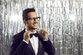 Happy handsome young ethnic man in tuxedo and stylish glasses adjusting his bow tie Royalty Free Stock Photo