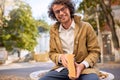 Happy handsome young man reading and posing with book outdoors. College male student carrying books in campus in autumn street. Royalty Free Stock Photo