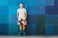 Happy handsome young roller in inline skates sitting against blu