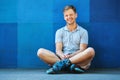 Happy handsome young roller in inline skates sitting Royalty Free Stock Photo