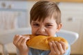 Happy handsome young teenage boy holding and eating freshly baked bread. Royalty Free Stock Photo