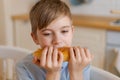 Happy handsome young teenage boy holding and eating freshly baked bread. Royalty Free Stock Photo