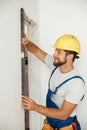 Happy handyman, builder in uniform smiling while measuring the wall using bubble level Royalty Free Stock Photo