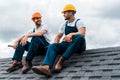 Handymen in helmets and uniform sitting on rooftop