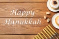 Happy Hanukkah. Flat lay composition with menorah, dreidels and sufganiyot on wooden table