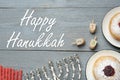 Happy Hanukkah. Flat lay composition with menorah, red candles, dreidels and sufganiyot on grey wooden table Royalty Free Stock Photo