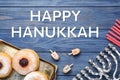 Happy Hanukkah. Flat lay composition with menorah, red candles, dreidels and sufganiyot on blue wooden table Royalty Free Stock Photo
