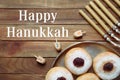 Happy Hanukkah. Flat lay composition with menorah, yellow candles, dreidels and sufganiyot on wooden table Royalty Free Stock Photo