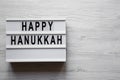 `Happy Hanukkah` word on modern board over white wooden background, top view. From above, flat lay