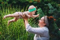 Happy harmonious family outdoors. mother throws baby up, laughing and playing in the summer on the nature. Royalty Free Stock Photo